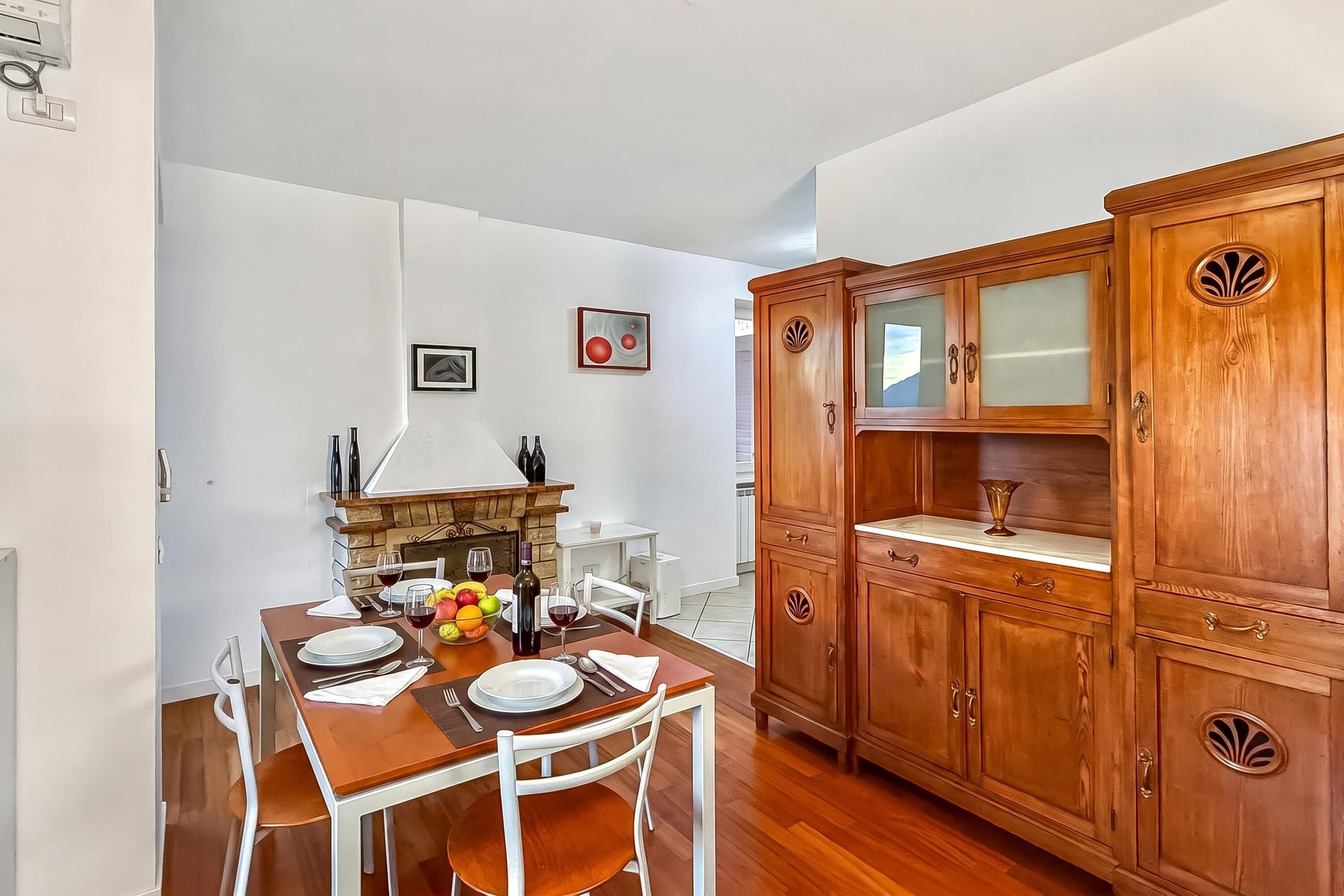 A dining area with a wooden table, chairs, a fireplace, and wooden cabinets.