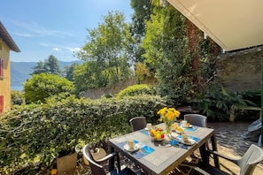 Un espace de restauration en plein air avec une table dressée pour deux personnes, entouré de verdure et offrant une vue sur les montagnes.