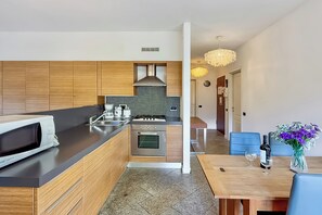 A modern kitchen with a microwave, stove, and sink. There is a dining area with a table and chairs, and a vase with flowers.