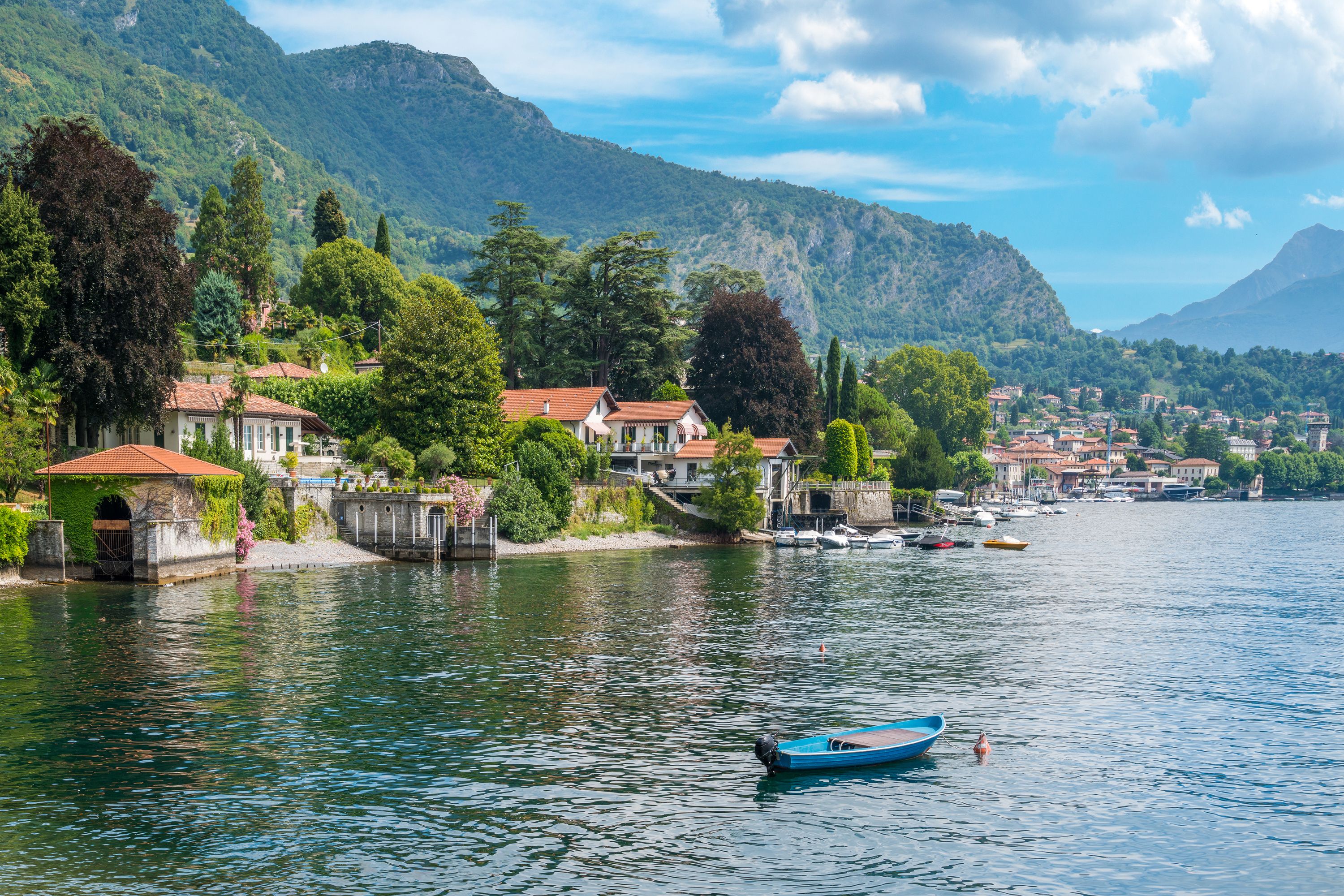 A lakeside village with houses along the shore, a small dock, and boats.