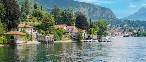 A lakeside village with houses along the shore, a small dock, and boats.