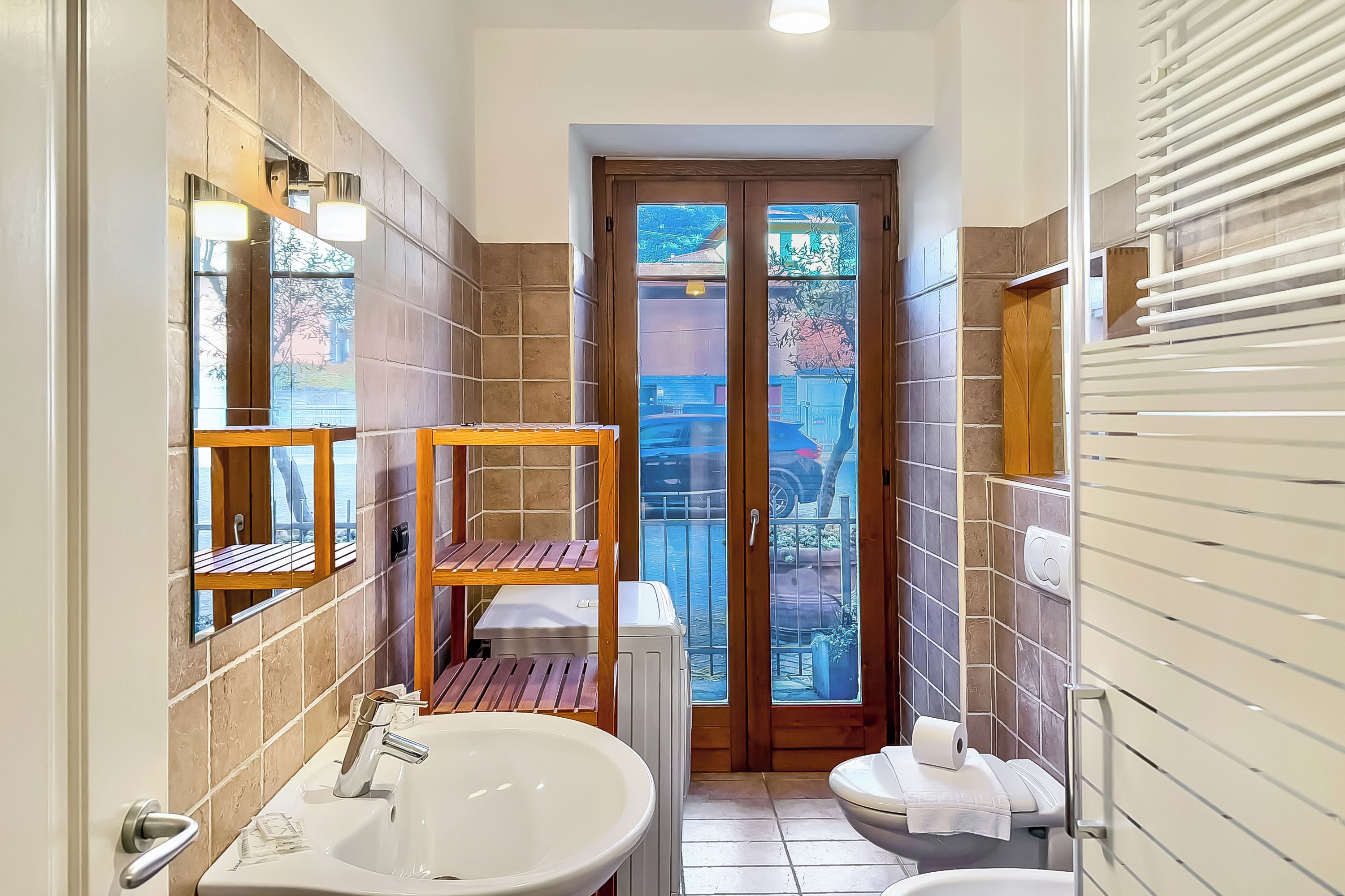 Un bagno con lavandino, WC e ripiano in legno.
