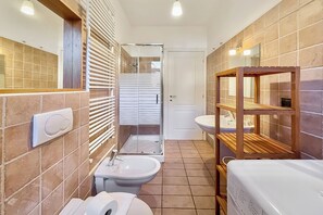 A bathroom with a toilet, bidet, sink, and shower.