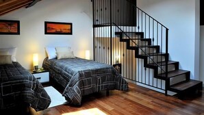 A bedroom with two beds, a wooden ceiling, a staircase, and artwork on the walls. - Regina Grande (Laglio)