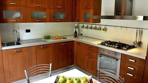 A modern kitchen with wooden cabinets, a gas stove, and a sink. - Regina Grande (Laglio)