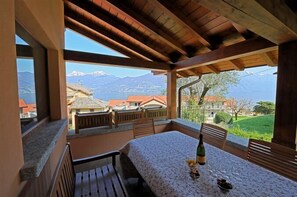 A balcony with a table, chairs, and a bottle of wine. - Villa Mimosa (Menaggio)