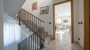 A staircase with black railings leading to a second floor. There are two framed pictures on the wall above the staircase. - Villa Antico (Tremezzina)