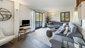 Un soggiorno moderno con un divano grigio, una TV a schermo piatto e un tappeto decorato.