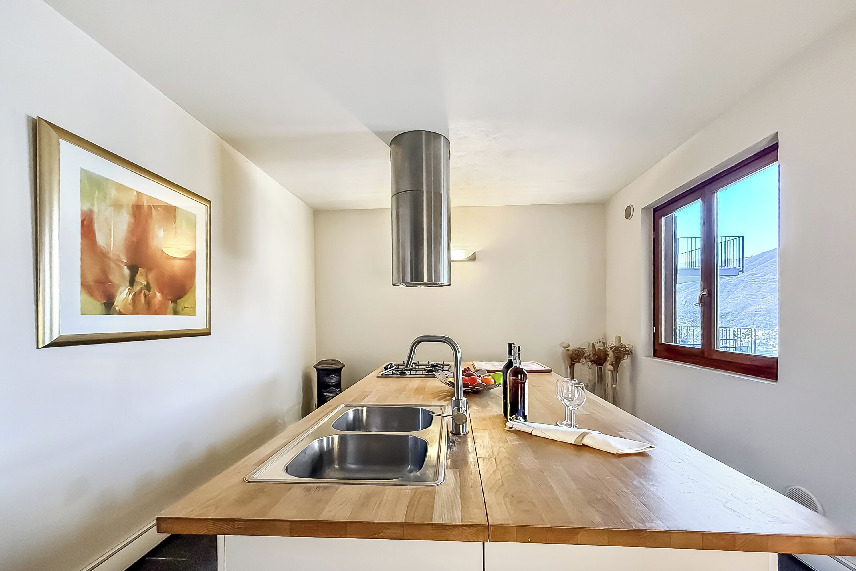 Una cucina con piano di lavoro in legno, lavello in acciaio inossidabile e una finestra vista esterna.