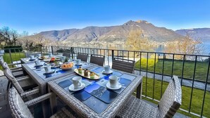 Un'area pranzo all'aperto con un tavolo apparecchiato per due, con vista su un paesaggio montuoso.