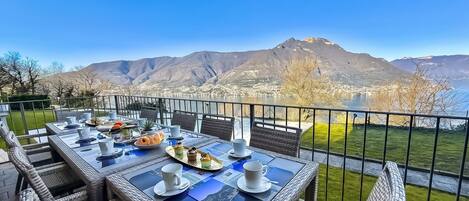 Un espace de restauration en plein air avec une table dressée pour deux personnes, offrant une vue sur un paysage montagneux.