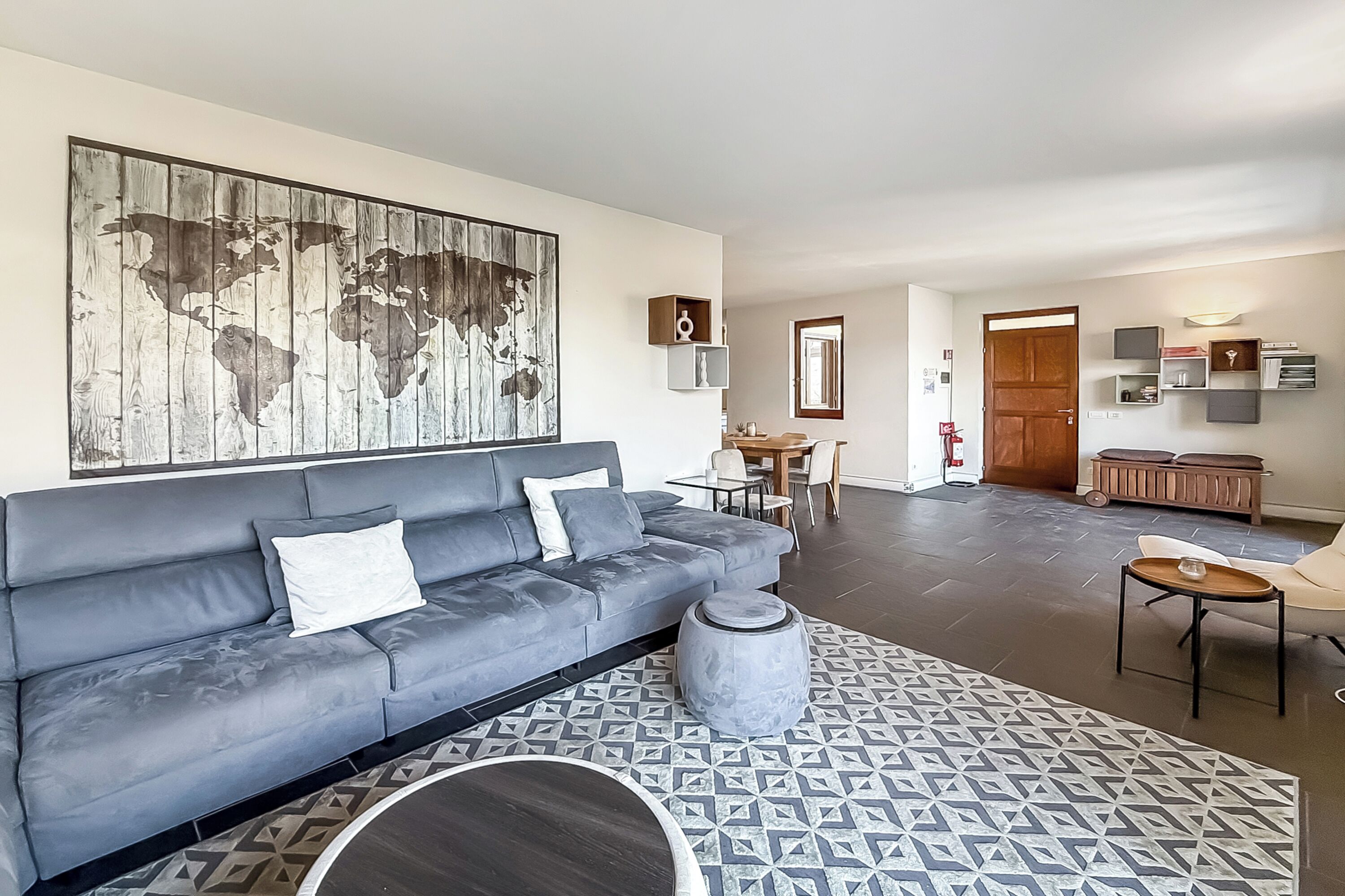 Un salon moderne avec un canapé gris, une table basse ronde et un tapis à motifs.