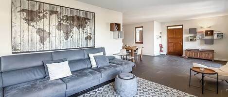 Un salon moderne avec un canapé gris, une table basse ronde et un tapis à motifs.