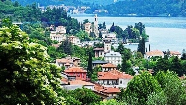 A coastal town with buildings along the water, a prominent tower, and lush greenery. - Belvedere Apt. 2 (Tremezzina)