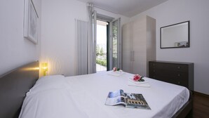 A hotel room with a bed, a nightstand with a lamp, a dresser, and a window with curtains. - Belvedere Apt. 3 (Tremezzina)