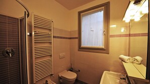 Ein kleines Badezimmer mit Toilette, Bidet, Waschbecken und einem Spiegel mit Handtuchhalter.