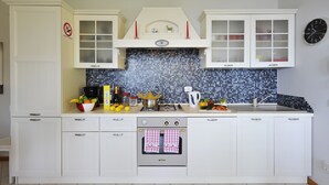 A kitchen with white cabinets, a tiled backsplash, a stove, and a sink. - Casa Monaco (Pianello del Lario)