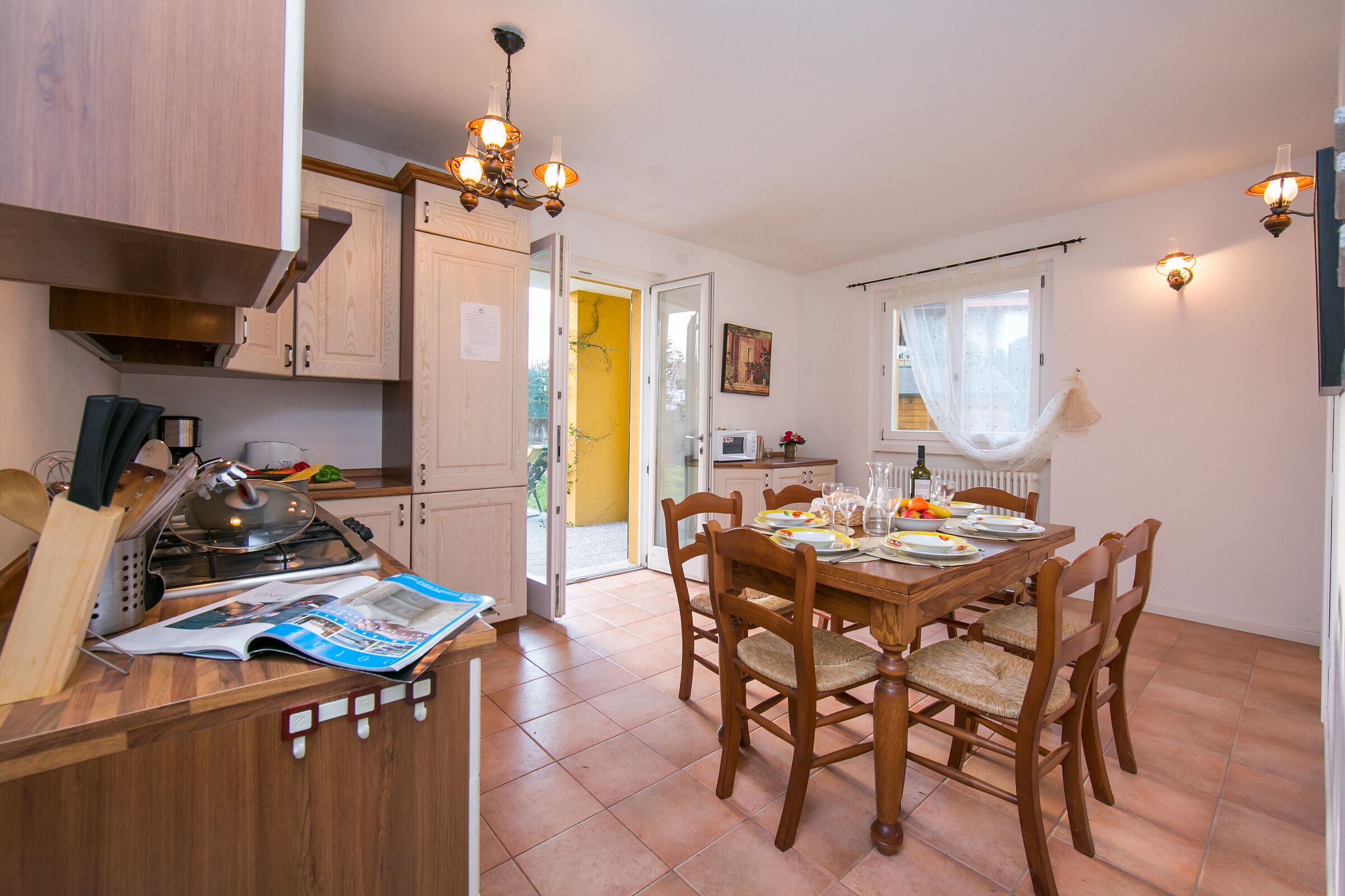 Een keuken met een fornuis, houten kastjes en een eethoek met een tafel gedekt voor vier personen.