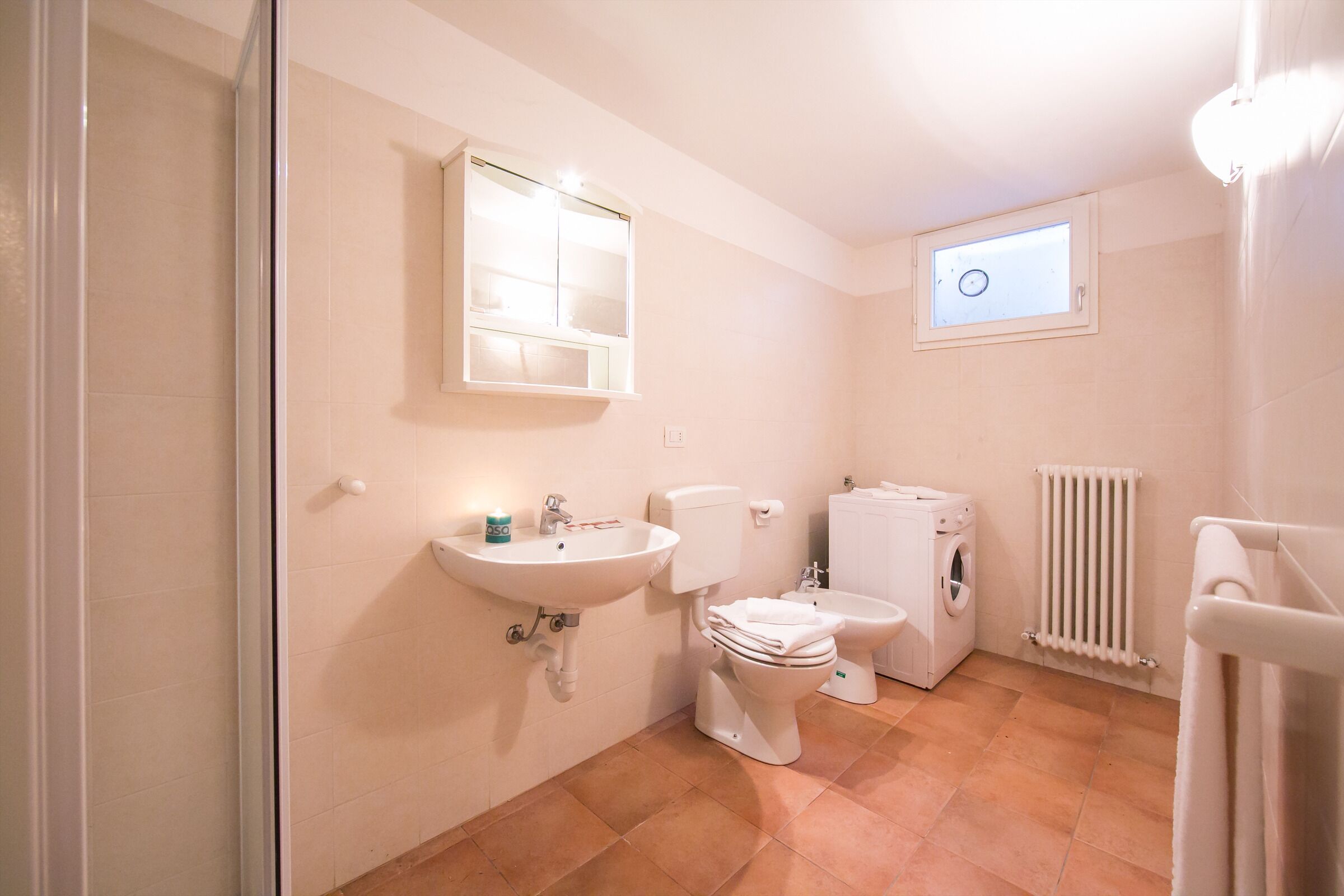 A bathroom with a sink, toilet, bidet, and washing machine.