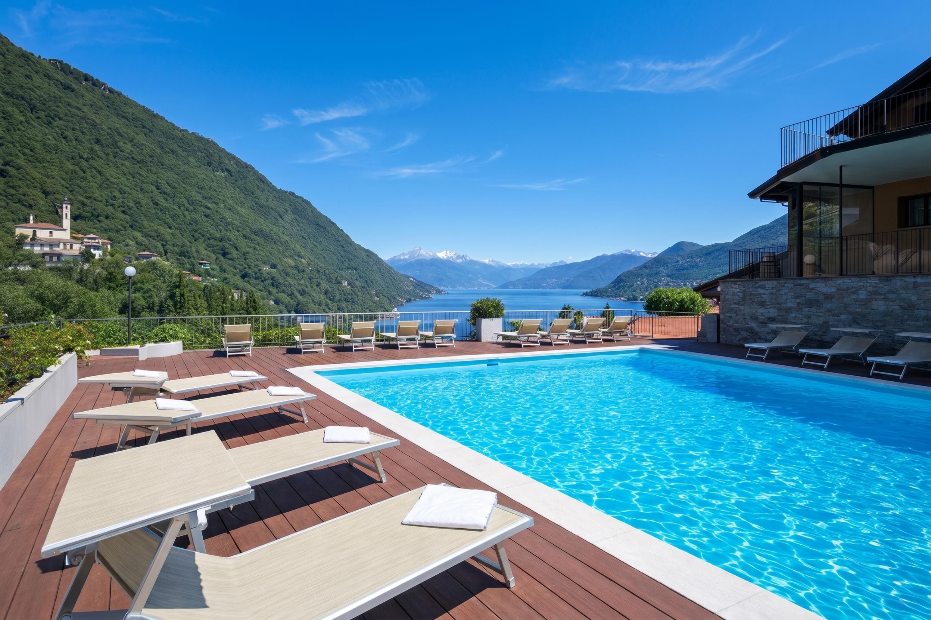 A swimming pool with lounge chairs, a view of a lake, and mountains in the background.