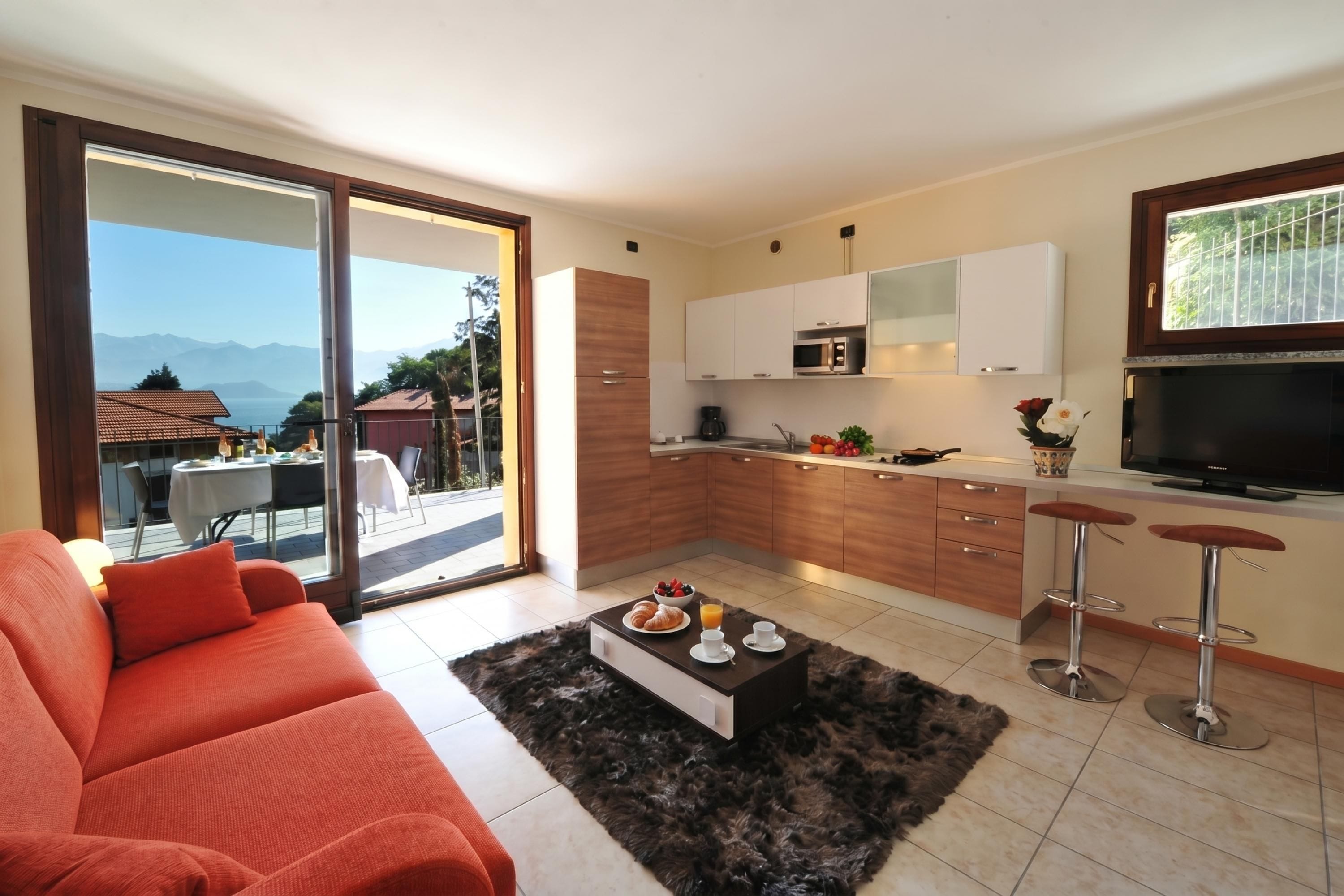 Una cocina moderna con un ventanal grande, un área de comedor con sofá y televisión.