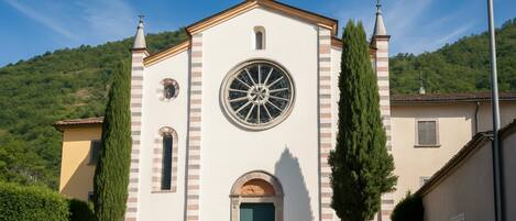 Una iglesia con un llamativo ventanal circular, un campanario y una escalera que conduce a la entrada.