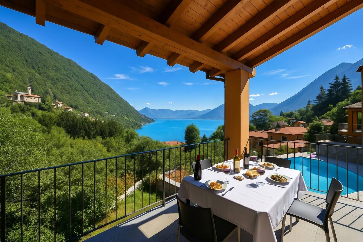 A balcony with a table set for dining, overlooking a mountainous landscape and a lake.