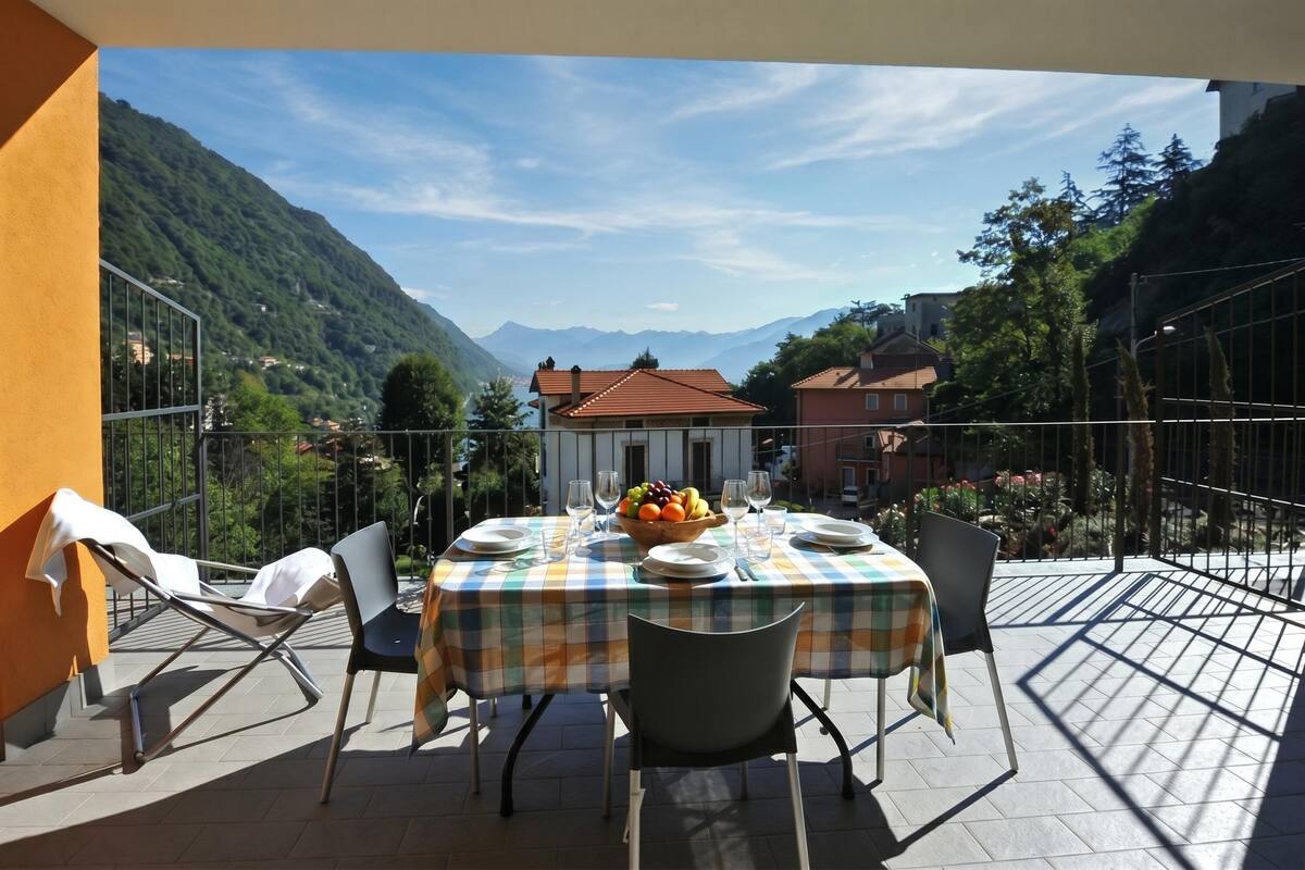 A terrace with a table set for dining, chairs, and a fruit bowl.