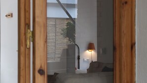 A room with a wooden door, a bed, a lamp, and a wall-mounted switch.