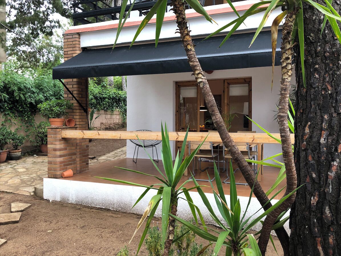 A house with a brick exterior, a wooden deck, and a covered patio area.