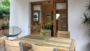 A wooden table and chairs in a covered patio area with a view of a garden.