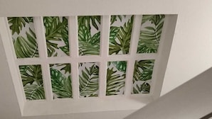 A ceiling with a window featuring a green leafy pattern.