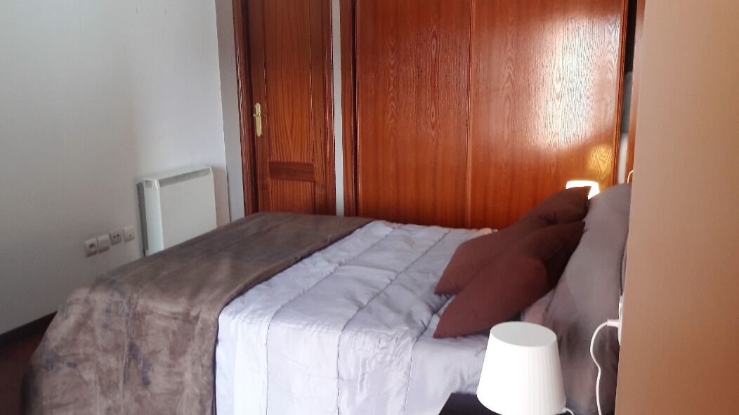 Un dormitorio con una cama, un armario de madera y una mesita de noche con lámpara.