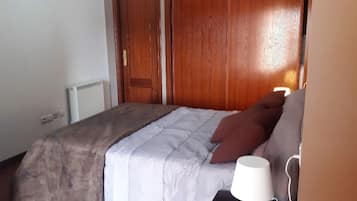 Un dormitorio con una cama, un armario de madera y una mesita de noche con lámpara.