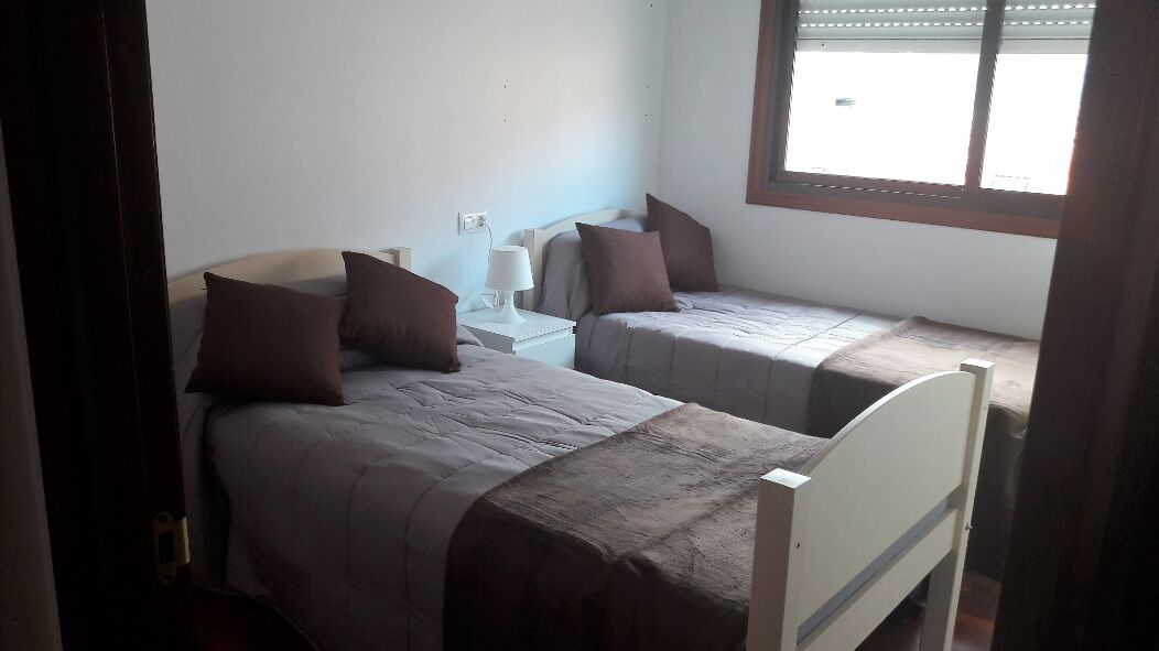 Una habitación con dos camas individuales, cada una con una almohada y una mesita de noche con lámpara.