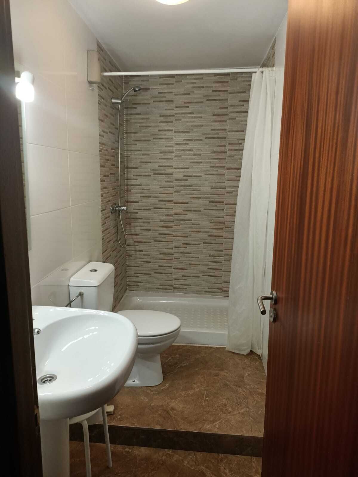 Een badkamer met douche, toilet en wastafel.