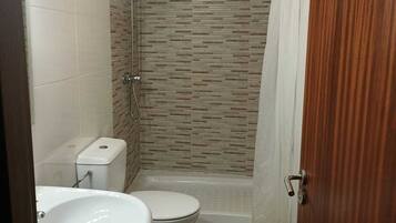 Een badkamer met douche, toilet en wastafel.