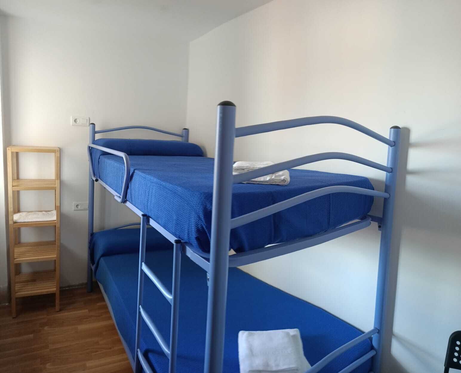 A bunk bed room with a wooden ladder and a small table.