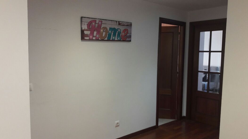 Un pasillo con un cartel que dice 'Home' en la pared, una puerta de madera y un ventanal con vistas.