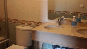 Un baño con inodoro, lavamanos y espejo.