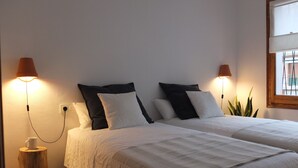 A hotel room with two beds, each with white and black bedding, and a small wooden stool with a cup on it. - Beach Apartment Entre Pinos P1 (Torredembarra)