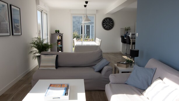 Una sala de estar moderna con un sofá modular, una mesa de centro y un comedor con mesa y sillas.