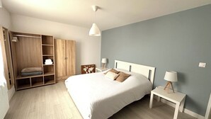 Un dormitorio con una cama grande, un armario, una mesita de noche y una lámpara.