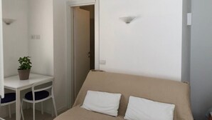 A small, clean room with a bed, a desk, and a chair.