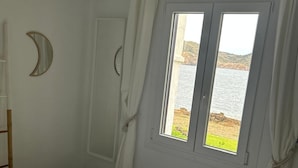 Un dormitorio con una cama, una ventana con cortinas, un ventilador de techo de madera y un equipo de aire acondicionado.