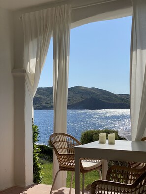 Un balcon avec une table et des chaises donnant sur un plan d’eau et des collines.