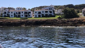 Vista costera con edificios blancos, costa rocosa y mar tranquilo.