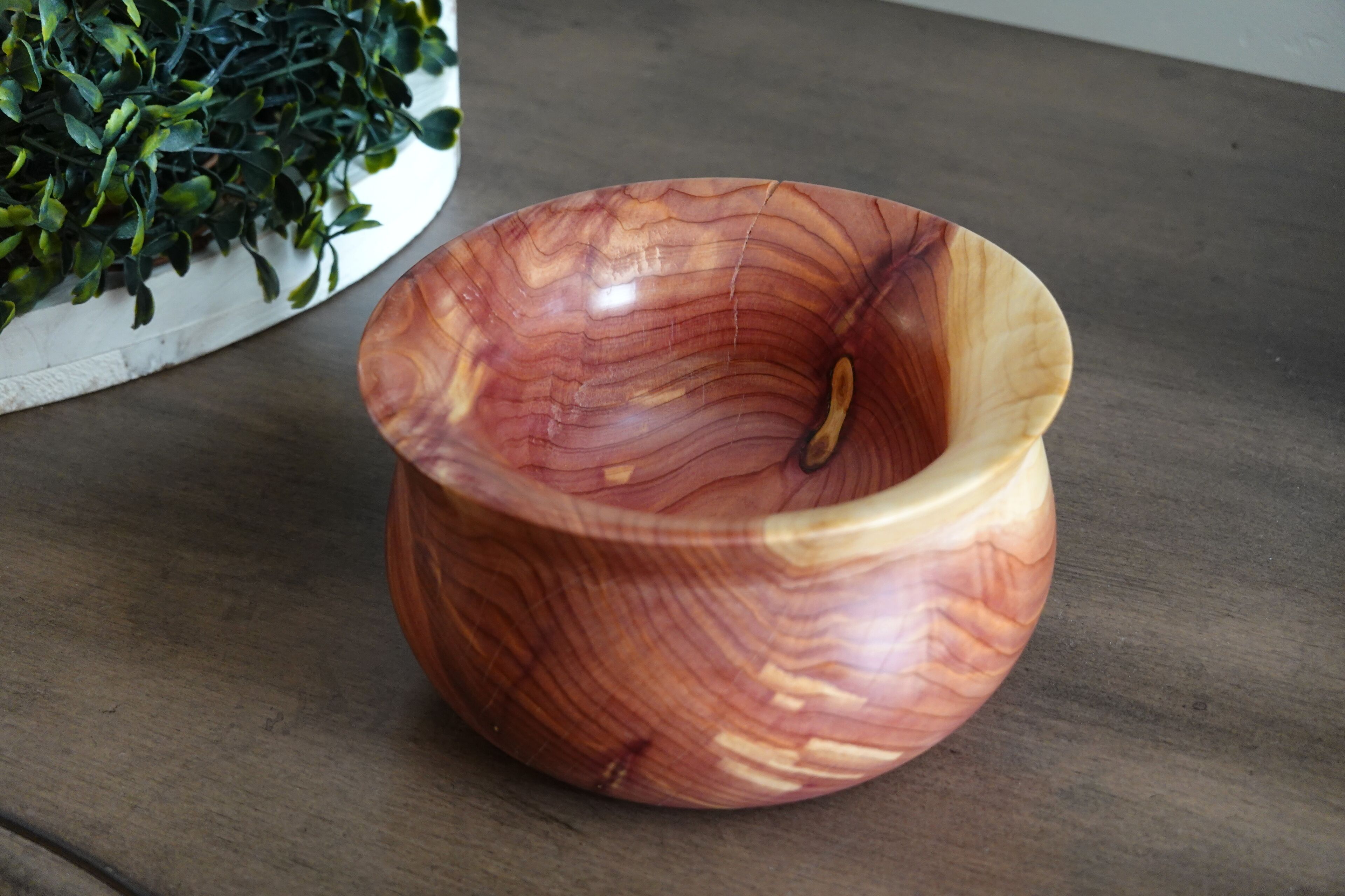 A wooden bowl with a glossy finish on a wooden surface.