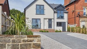 A modern two-story house with a paved driveway and a stone wall. - Host & Stay | The Hampton at Prospect Hill Apartments (Whitby)