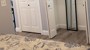 Un dormitorio con una cama, un armario y una puerta que da a otra habitación.